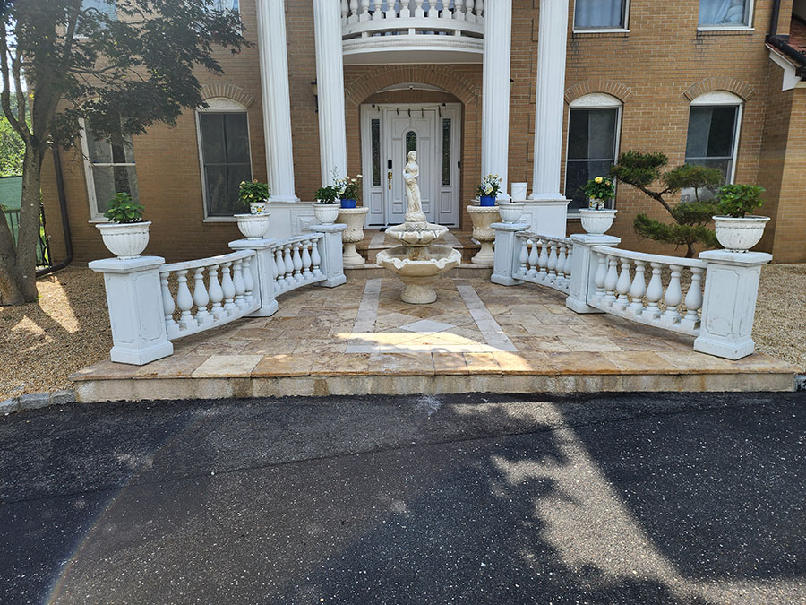 A large white house with a fountain in front, surrounded by greenery and a clear blue sky.