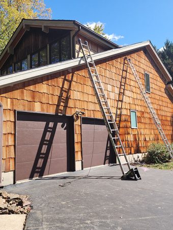 A man is using a ladder to work on the exterior of a house.