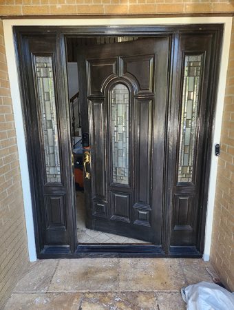 A black door featuring a rectangular glass panel in the upper section.