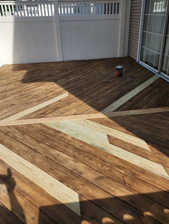 A wooden deck with a distinct shadow cast across its surface, highlighting the texture and grain of the wood.