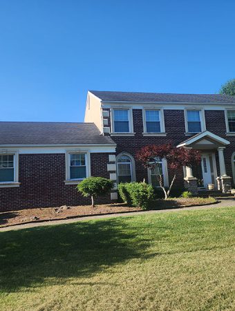 A large brick house with a spacious lawn in front, showcasing a well-maintained outdoor area.